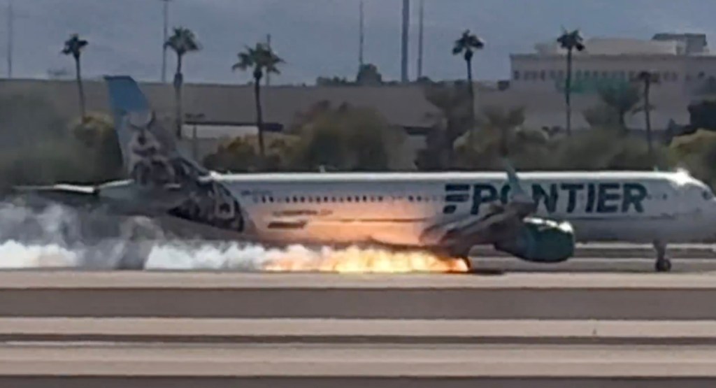 The plane on the runway with fire shooting out.