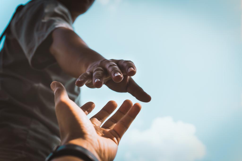 Two hands reaching out to help each other in a dark setting