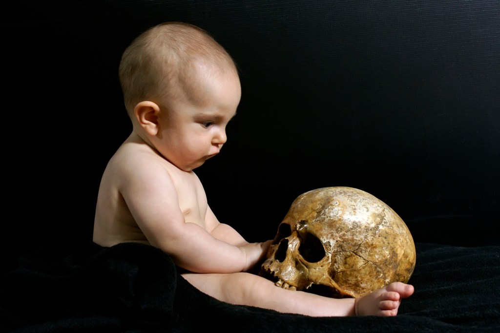 A baby holding a skull, symbolizing Pluto's oversight of birth and death cycles