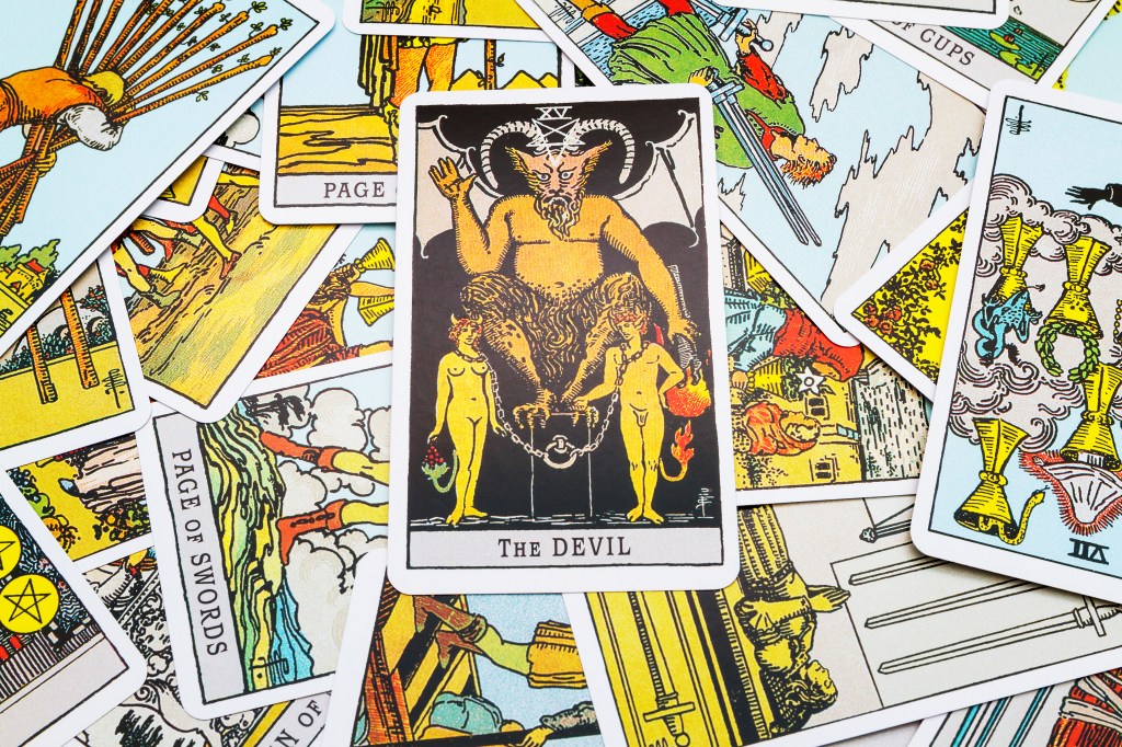 Devil tarot card associated with Capricorn prominently displayed in the foreground