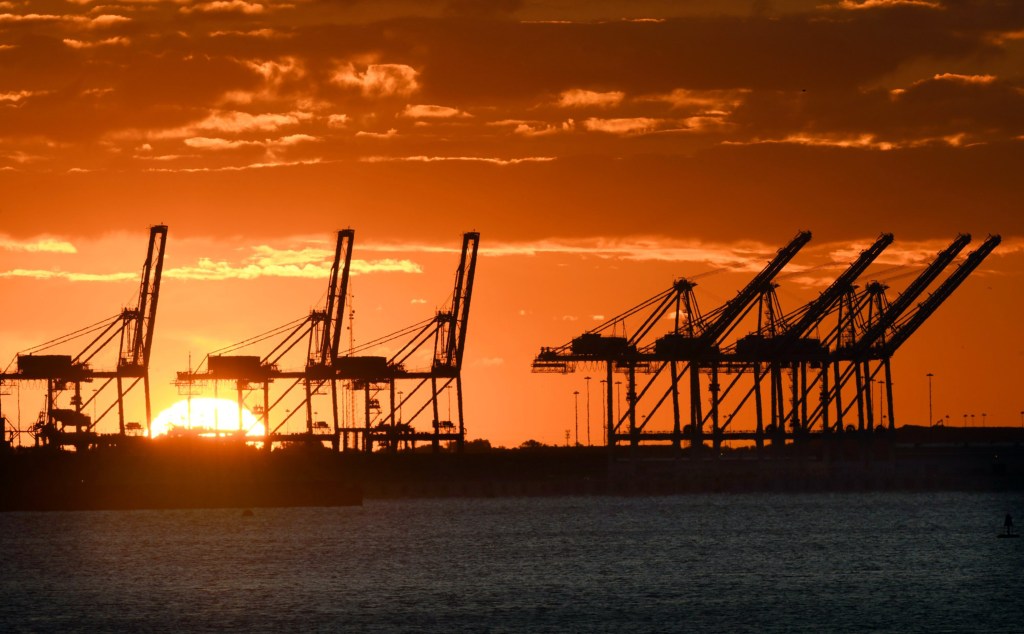 cranes at the Port of Baltimore are silhouetted against the sunrise. 