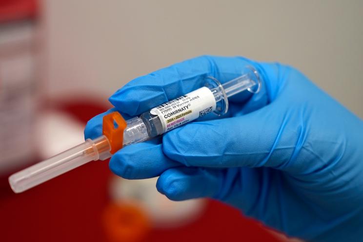 A pharmacist holds a COVID-19 vaccine at a pharmacy in New York, on Tuesday, Sept. 24, 2024.