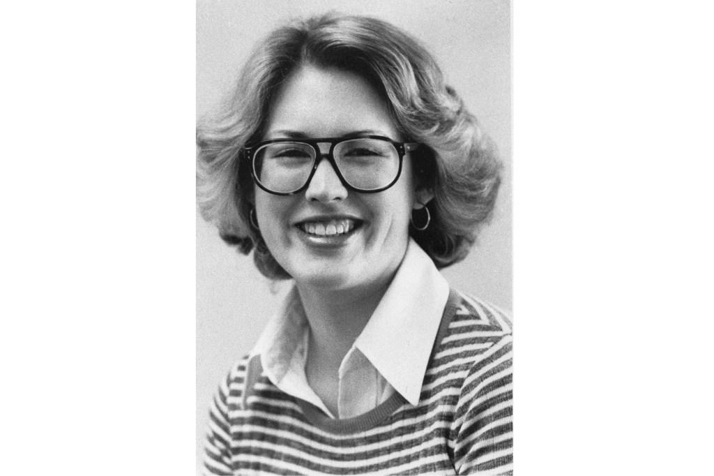 Megan Marshack in 1976, wearing glasses and a striped shirt, known for being present at Nelson Rockefeller's office during his fatal heart attack