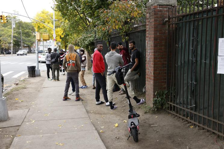 Migrants stand outside of the Migrant center