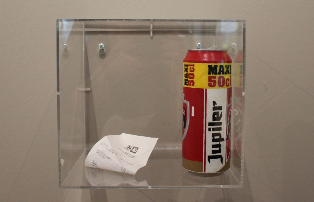 Beer can artwork and receipt in a glass case.