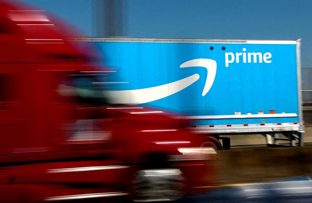 Red truck driving past Amazon Prime truck.