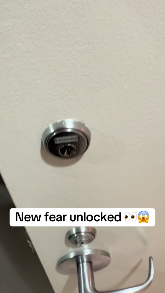 Man discovering an unusual keyhole on a hotel room's bathroom door