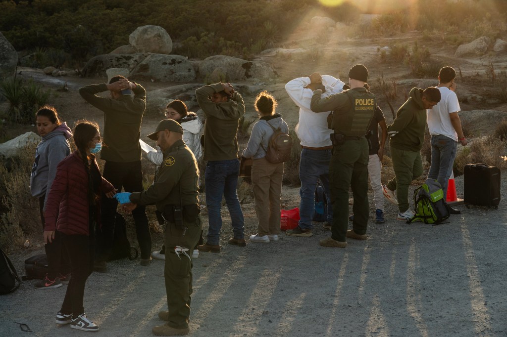 Border Patrol agents search a group of migrants who had entered California illegally from Mexico.