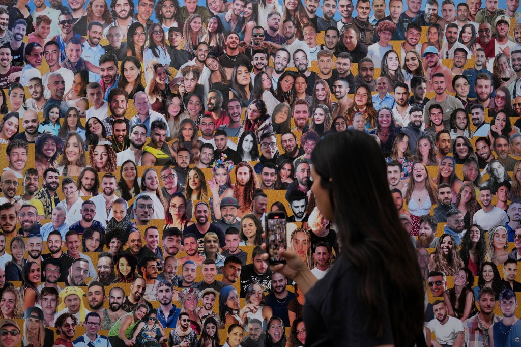 Attendant walking through a mural containing portraits of the victims from the Nova music festival attack, near Kibbutz Reim, southern Israel