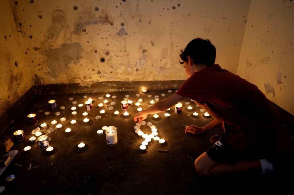 A boy lighting memorial candles in a bomb shelter on the first anniversary of the October 7 attack near Kibbutz Mefalsim, southern Israel