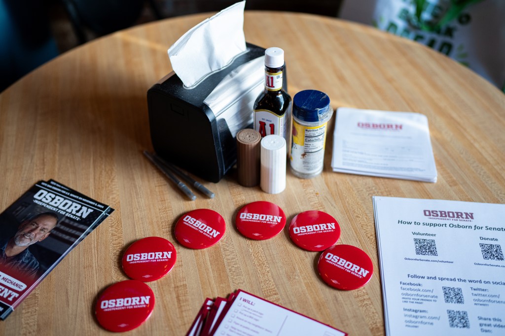 Osborn buttons and campaign materials on a table during a campaign stop at at Sly's Family Bar and Grill in Neligh, Neb. on Oct. 14, 2024.