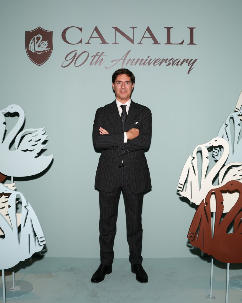 Stefano Canali in a suit at Canali's 90th Anniversary party in New York, standing in front of a wall with swans