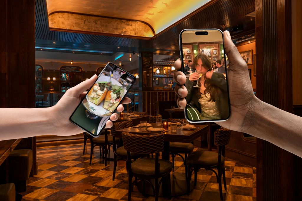 Composite: A pair of hands holding cell phones over a dining table with chairs.