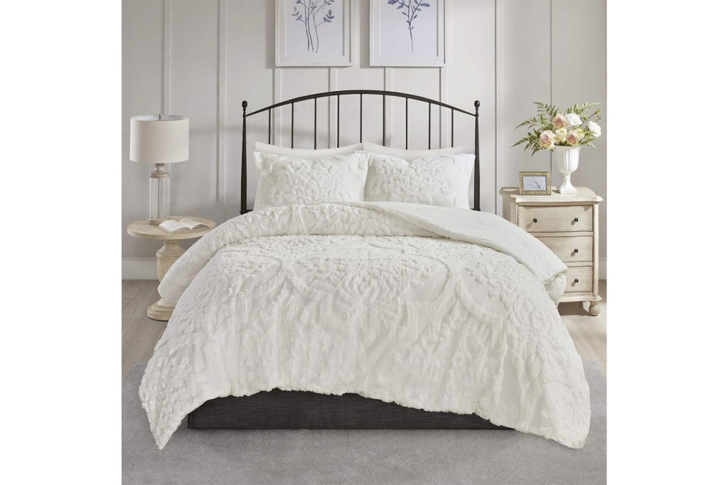 A bed with a white comforter and pillows