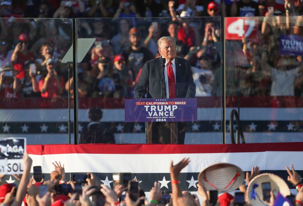 Donald Trump speaking at a podium during his campaign rally in Coachella, California, with a crowd of people in the background on Oct. 12, 2024.