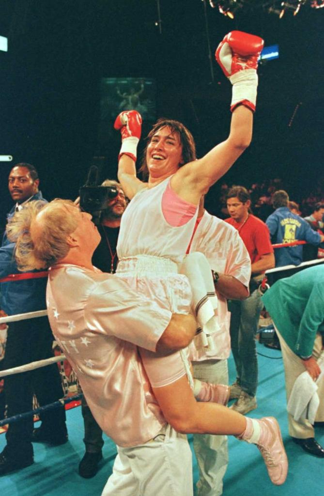 Female boxer Christy Martin is held up by her husband Jim Martin after winning championship.