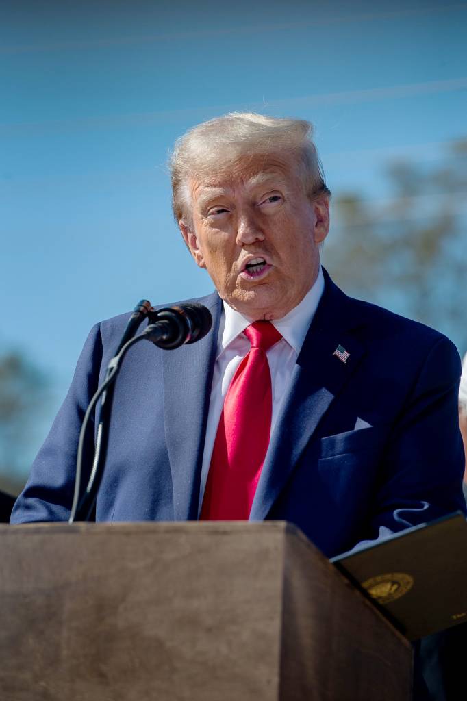 Former President Donald Trump giving a speech in Swannanoa, wearing a suit and tie and speaking into a microphone on October 21, 2024