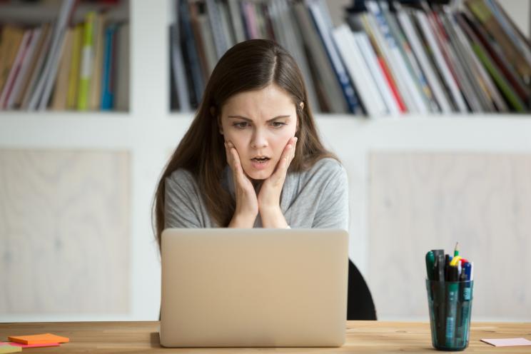 A stunned woman reading something on her laptop.