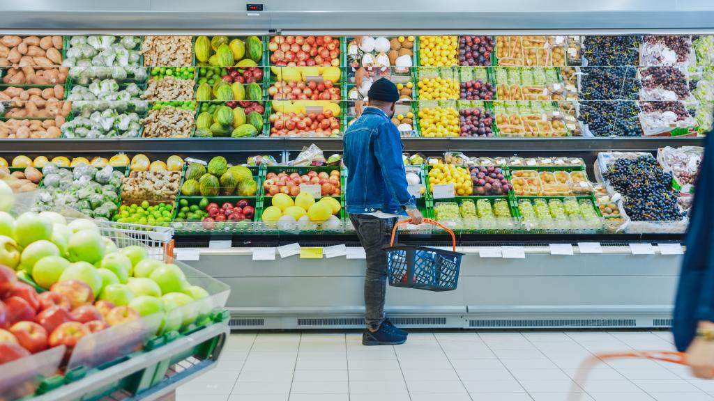 Happy black man shopping for organic fruits and vegetables in the fresh produce section of a supermarket