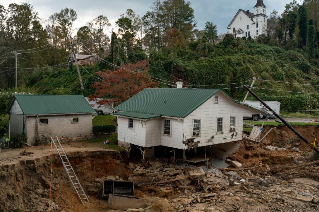 A house teetering on collapse at the edge of a riverbank.