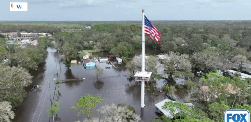 Flooded homes and schools in Valrico, Florida, with a flag standing in water after Hurricane Milton