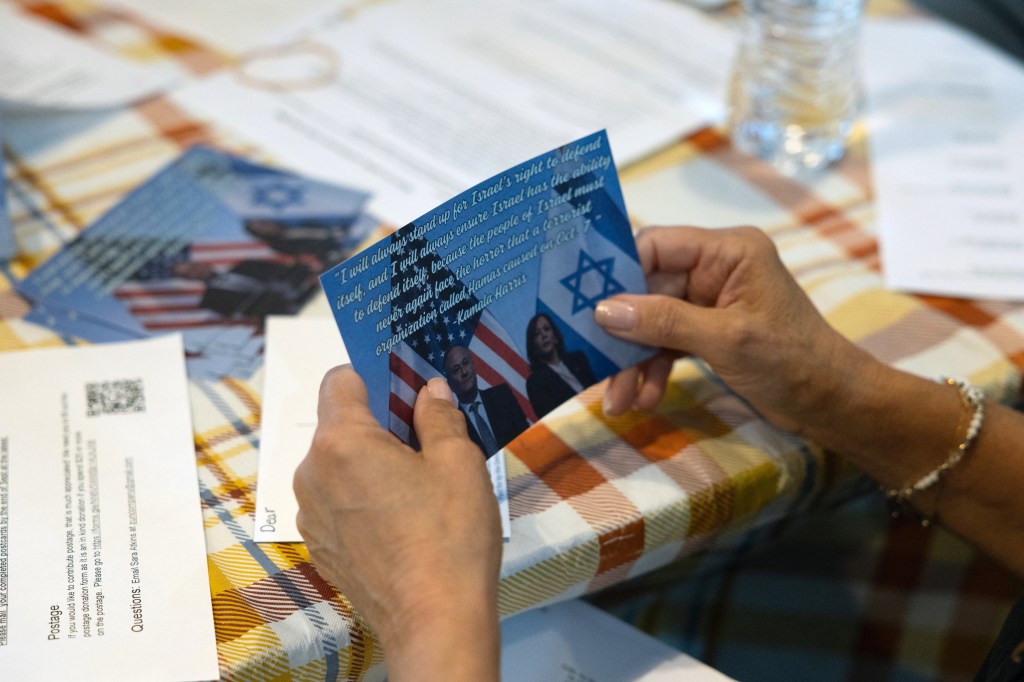 Ilene Miller holding a postcard featuring Vice President Kamala Harris and Second Gentleman Doug Emhoff, prepared for distribution to Jewish voters in Wynnewood, Pennsylvania