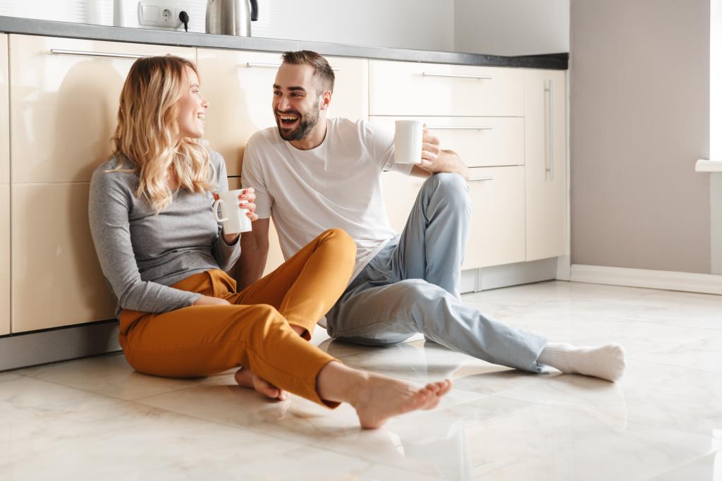 Image of amazing young loving couple sitting at the kitchen drinking tea on a floor.