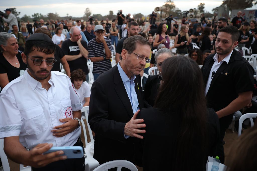 Israeli President Isaac Herzog embraces a family member of victims killed at the Supernova music festival while attending a gathering in memory of their relatives, at the Supernova memorial site for the victims 