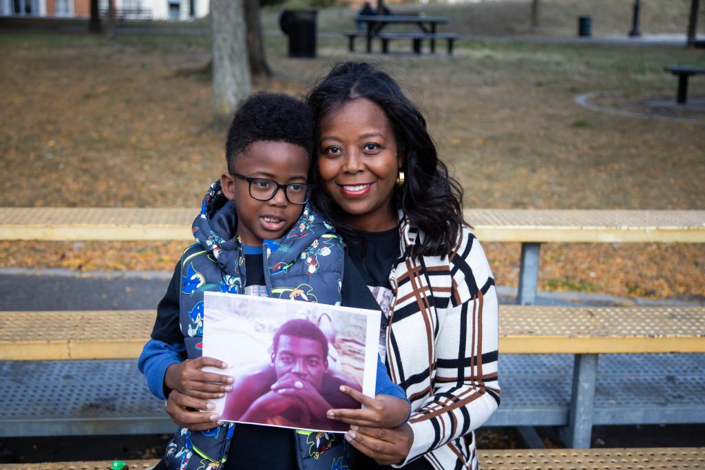 The mother and son on a bench holding a photo of her slain police officer father.