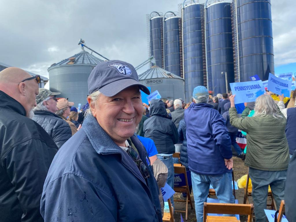 Joe Logan smiles at camera with silos in the background.