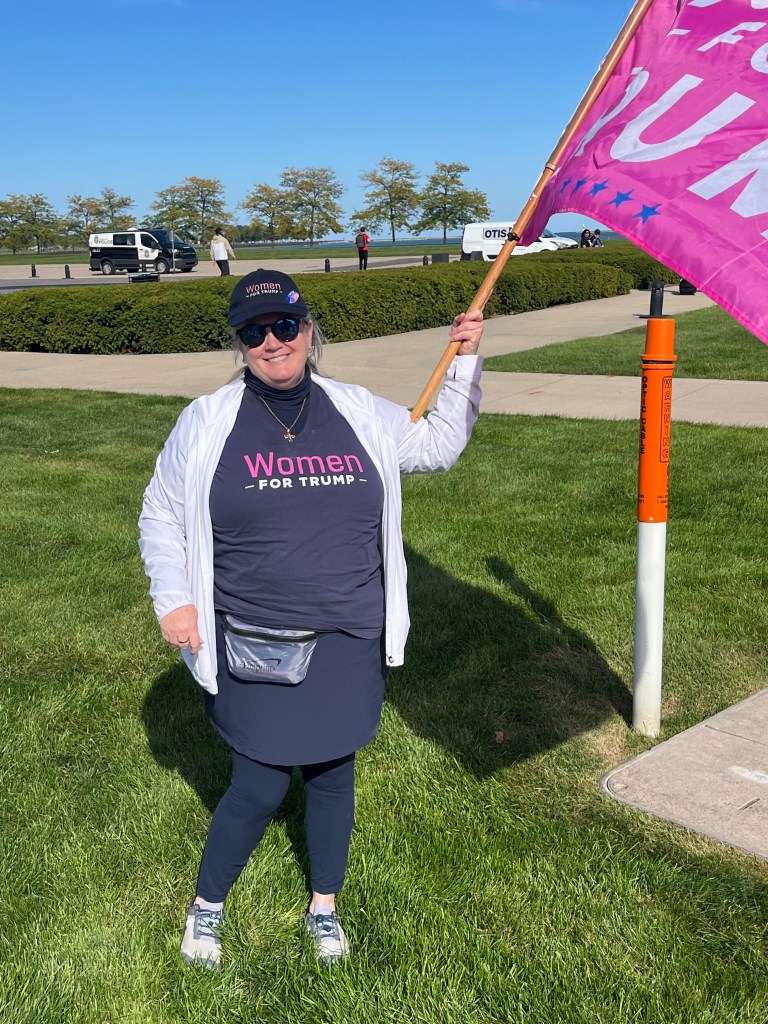 Laura Palus from Brookfield, Wisconsin, holding a pink flag while waiting outside of the Trump school choice event in Milwaukee