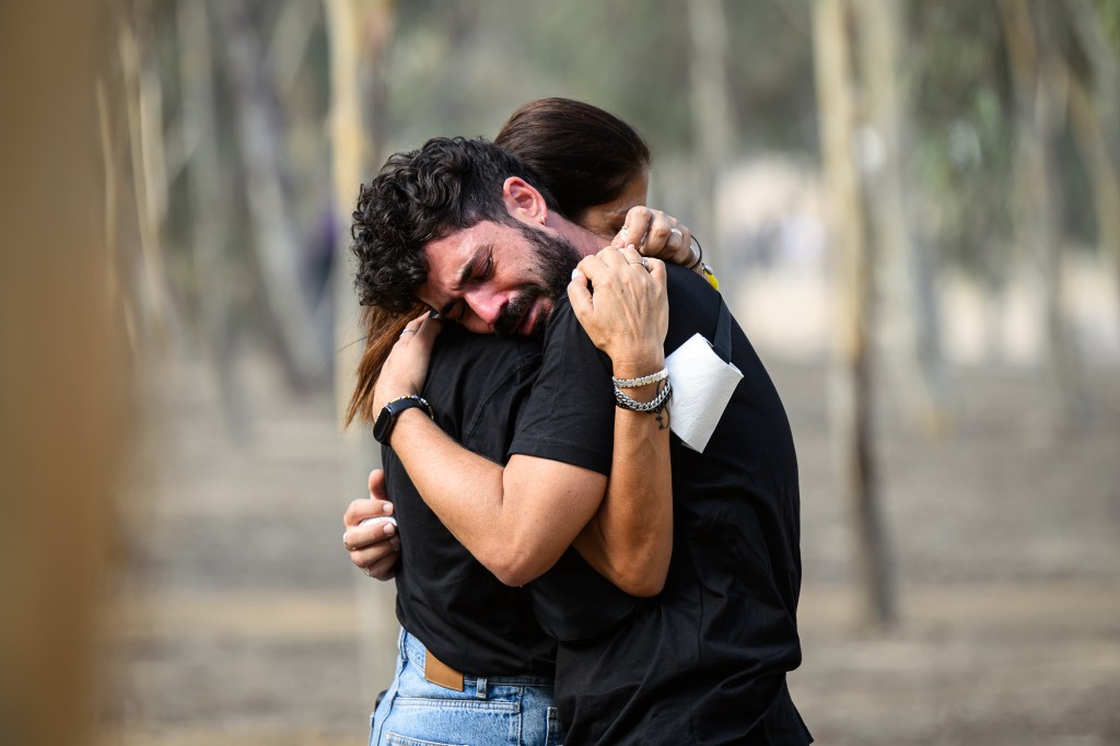 A man and woman embracing at a gathering in Re'im, Israel, to commemorate the anniversary of Hamas October 7 attacks