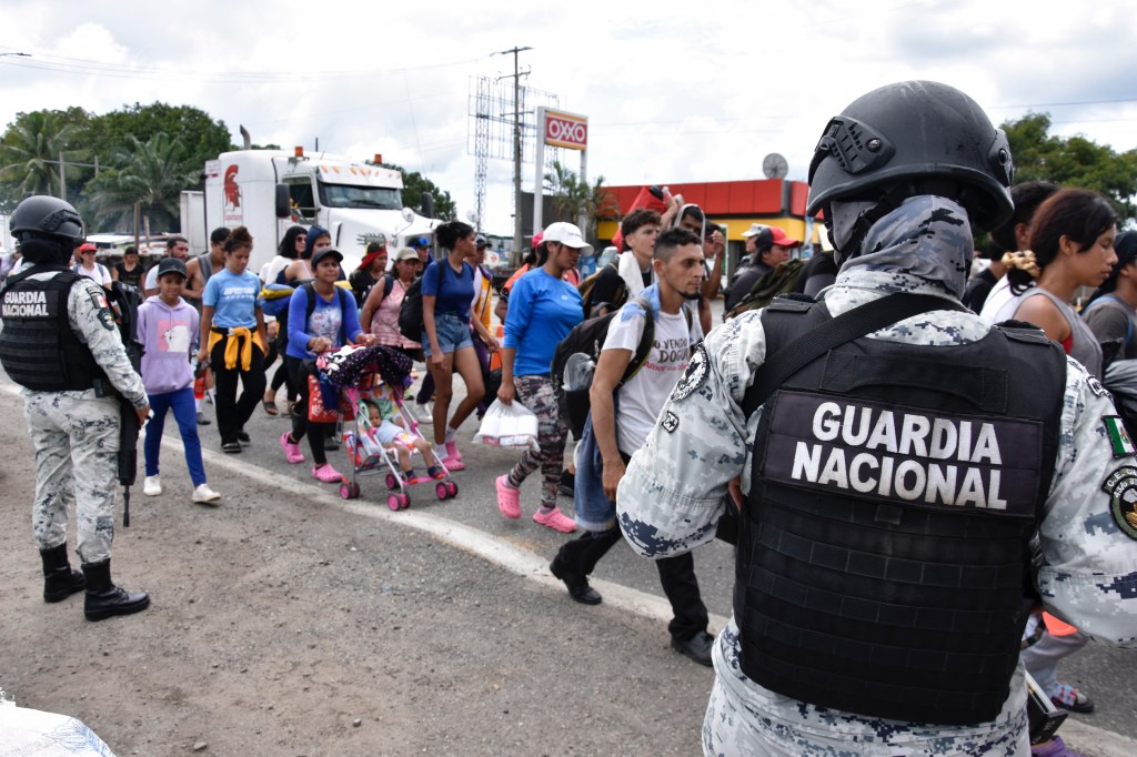 Members of the Mexican National Guard observe the migrants of different nationalities walk towards the United States 