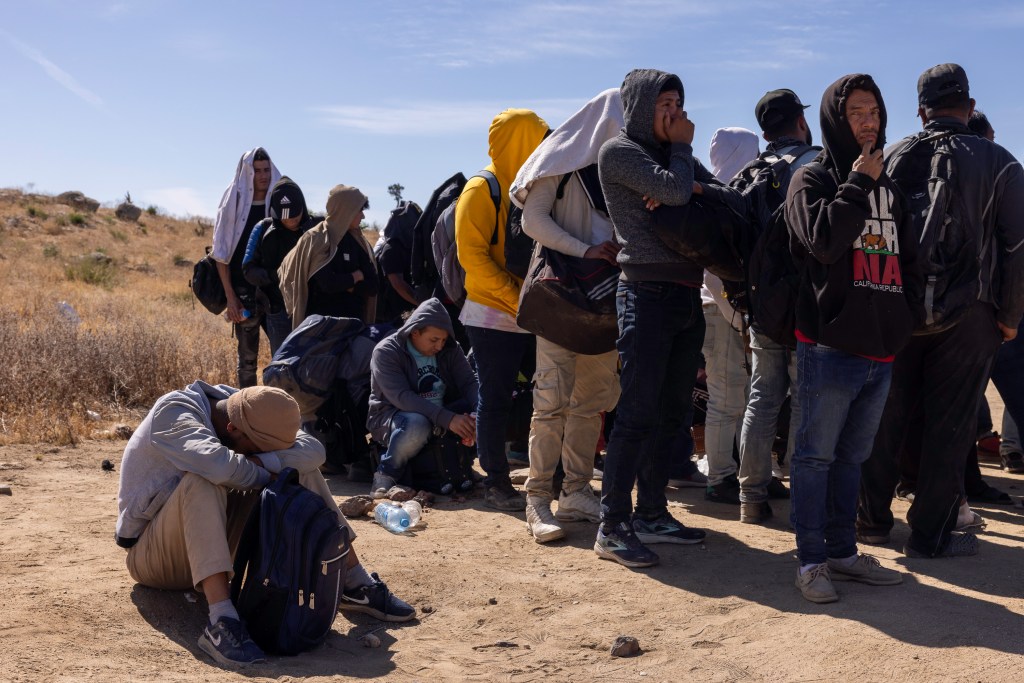 Dozens of migrants wait to be taken into federal custody after crossing the California border illegally.