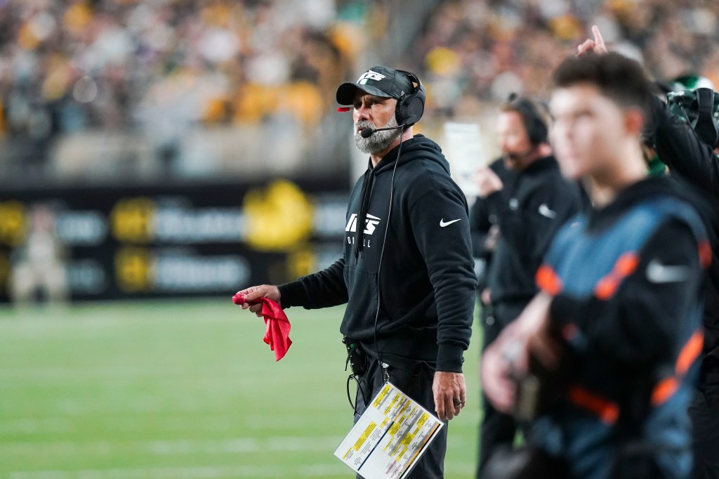 Jets head coach Jeff Ulbrich holds a challenge flag