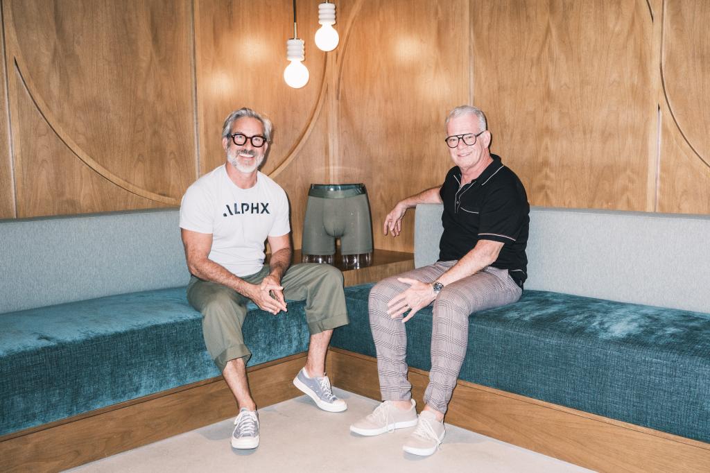 Co-founders of ALPHX, Garrett Swann and Tom Speight, sitting on a couch at a promotional event in New York, NY