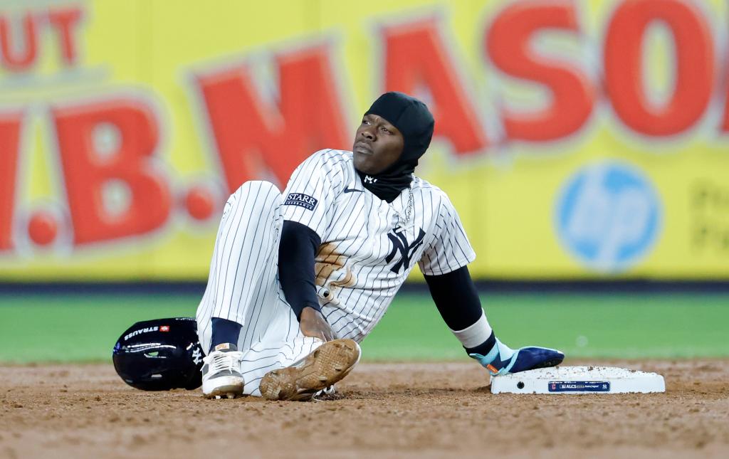 New York Yankees third baseman Jazz Chisholm Jr. sitting on the ground, reacting after being picked off while attempting to steal a base during the 6th inning of the ALCS game at Yankee Stadium.