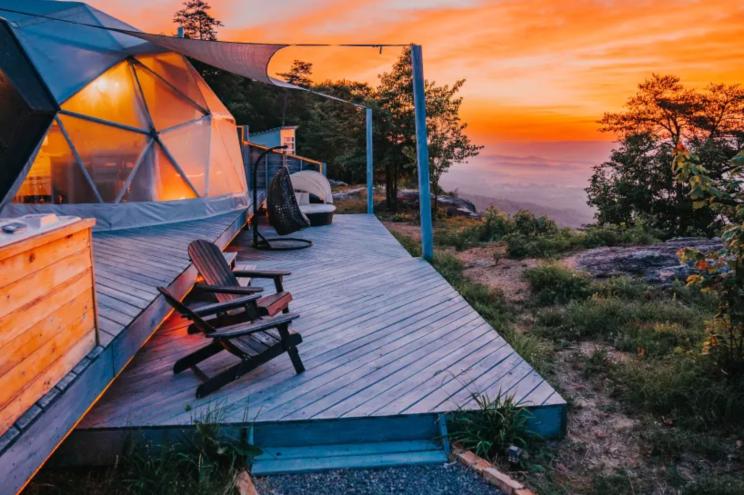 A wooden deck with chairs and a dome, part of an American treesort