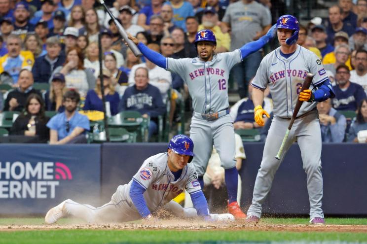 Jose Iglesias slides into home plate as the Mets' Francisco Lindor and Pete Alonso look on.