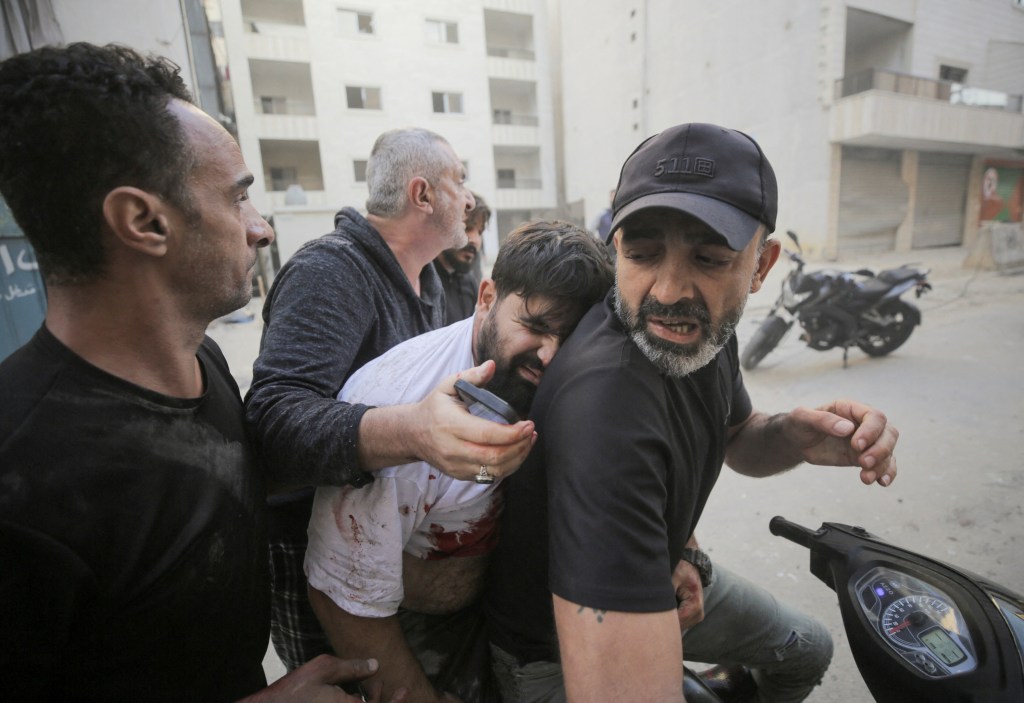 People tried to move a wounded man after an Israeli strike on the Mreijeh neighborhood in Beirut's southern suburbs.