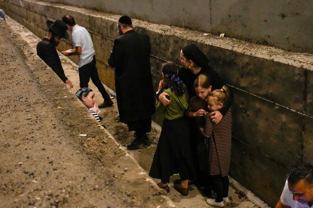 People take cover on the side of the road as a siren sounds a warning of incoming missiles fired from Iran on a freeway in Shoresh, between Jerusalem and Tel Aviv in Israel.