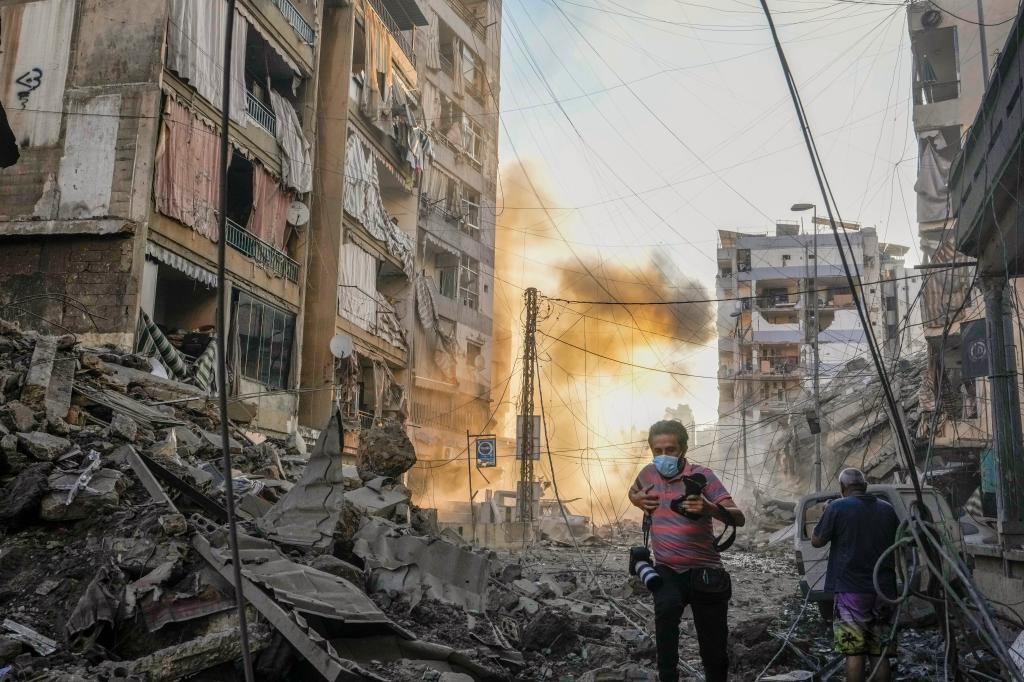 A photographer runs for cover following an Israeli airstrike in a suburb south of Beirut.