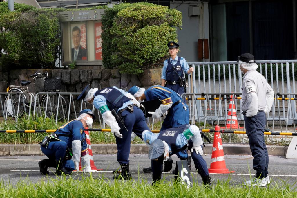 Police investigate the grounds outside the headquarters of Japan's Liberal Democratic Party following the firebomb attack.