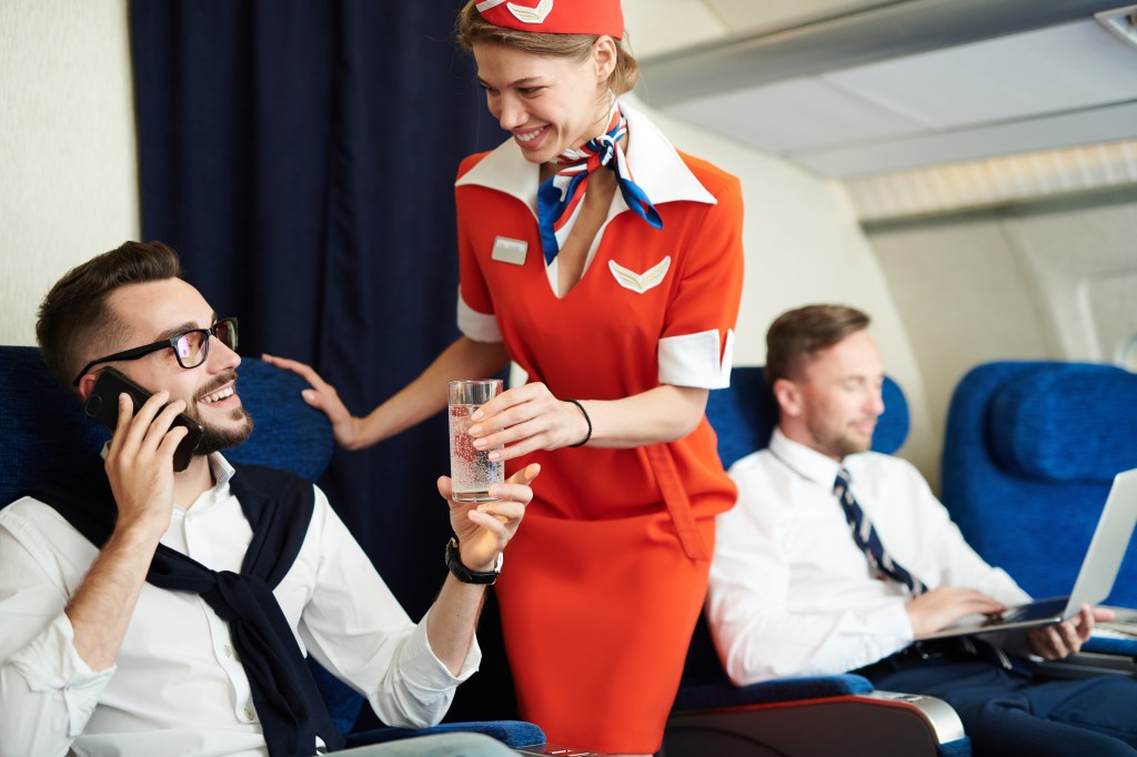 Passenger and flight attendant smiling at one another. 