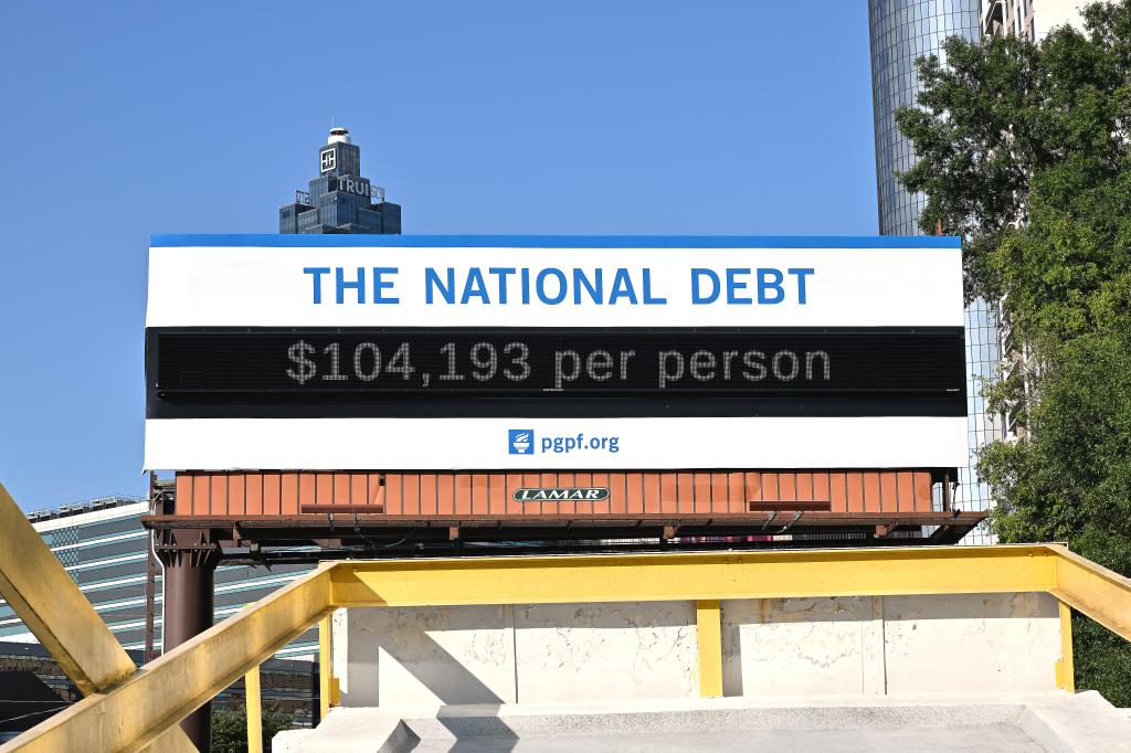 A poster and electronic billboard displayed near Ted Turner Dr and Marietta St that displays the current U.S. National debt per person and as a nation at 35 Trillion dollars on August 08, 2024 in Atlanta, Georgia.