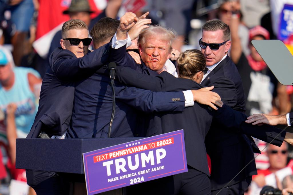 Former President Donald Trump being assisted off the stage at a Republican campaign event in Butler, Pa., on July 13, 2024