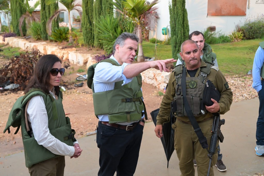 Dave McCormick stands with IDF soldier at Kibbutz pointing.