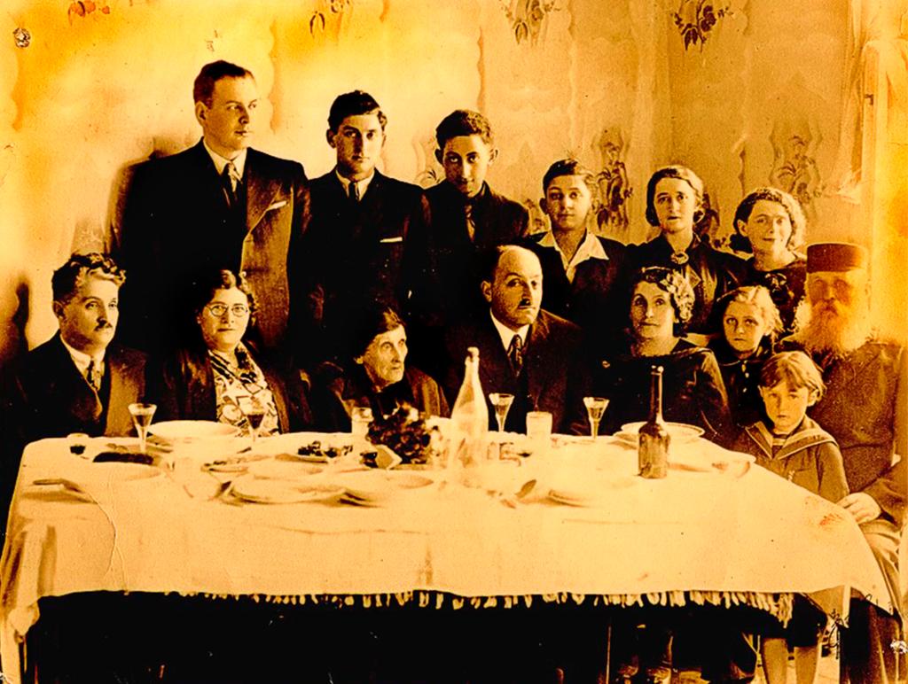 Old yellow-ish photo of Rona Kaufman's maternal grandfather's family at a dinner table.