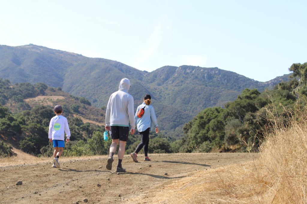 A group of people walking on a dirt path in Santa Barbara County, admiring mountain views at Alma Rosa Winery.