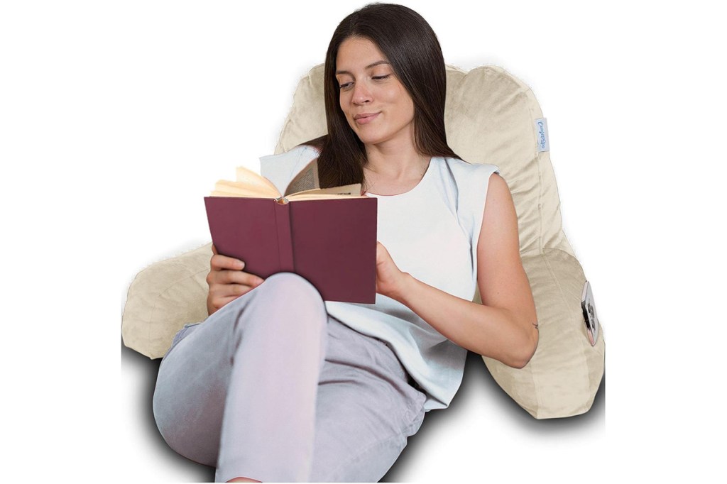 A woman reading a book on a seat pillow